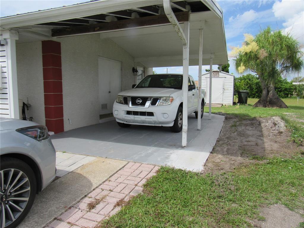 A white pickup truck is parked under a covered carport attached to a residential home — 6273 SOONER STREET, NORTH PORT, FL