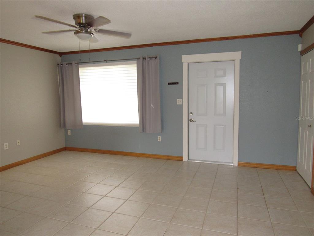 A room with light-colored tile flooring, a ceiling fan, a window with curtains, and a door — 6273 SOONER STREET, NORTH PORT, FL