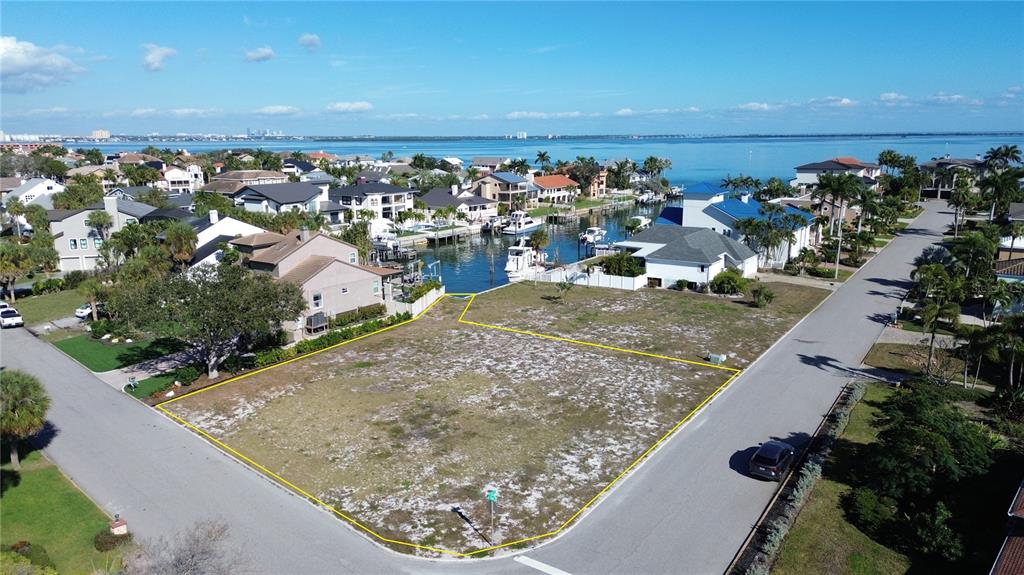 An aerial view shows a vacant, corner residential lot bordering a canal with docked boats — 139 9TH STREET E, TIERRA VERDE, FL
