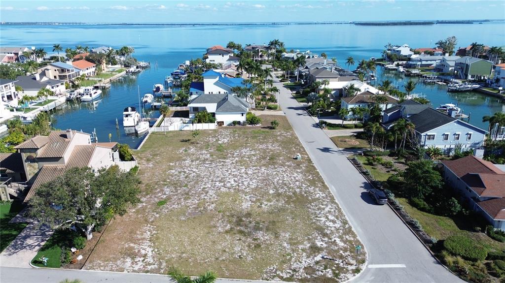 An aerial view shows a vacant waterfront lot situated between two residential streets — 139 9TH STREET E, TIERRA VERDE, FL