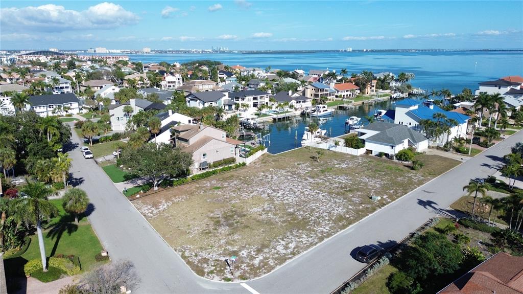 An aerial view shows a vacant, grassy corner lot situated near a residential canal — 139 9TH STREET E, TIERRA VERDE, FL