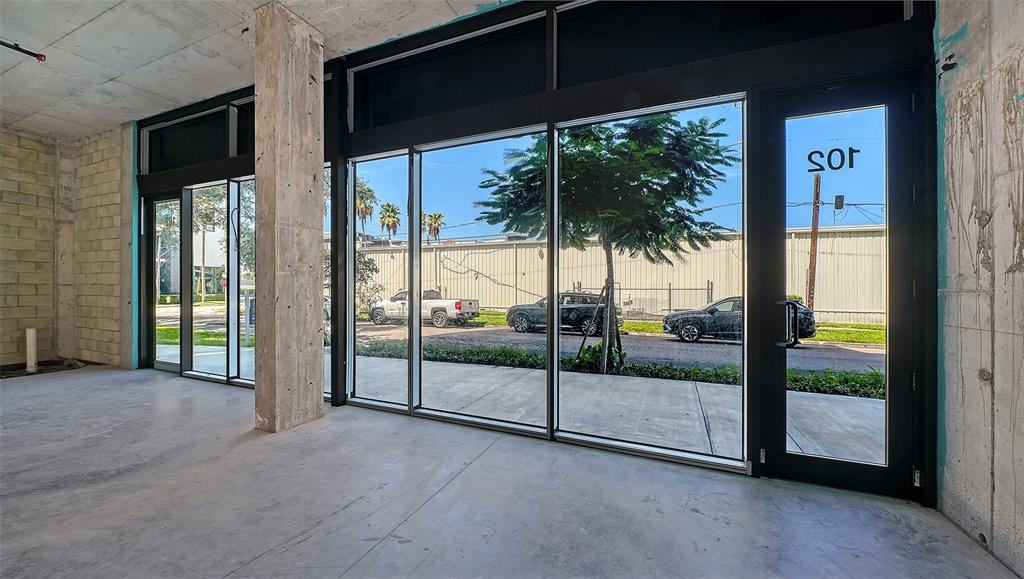 An unfinished commercial space features concrete floors, exposed walls, and large floor-to-ceiling glass windows — 430 KUMQUAT COURT UNIT 102, SARASOTA, FL