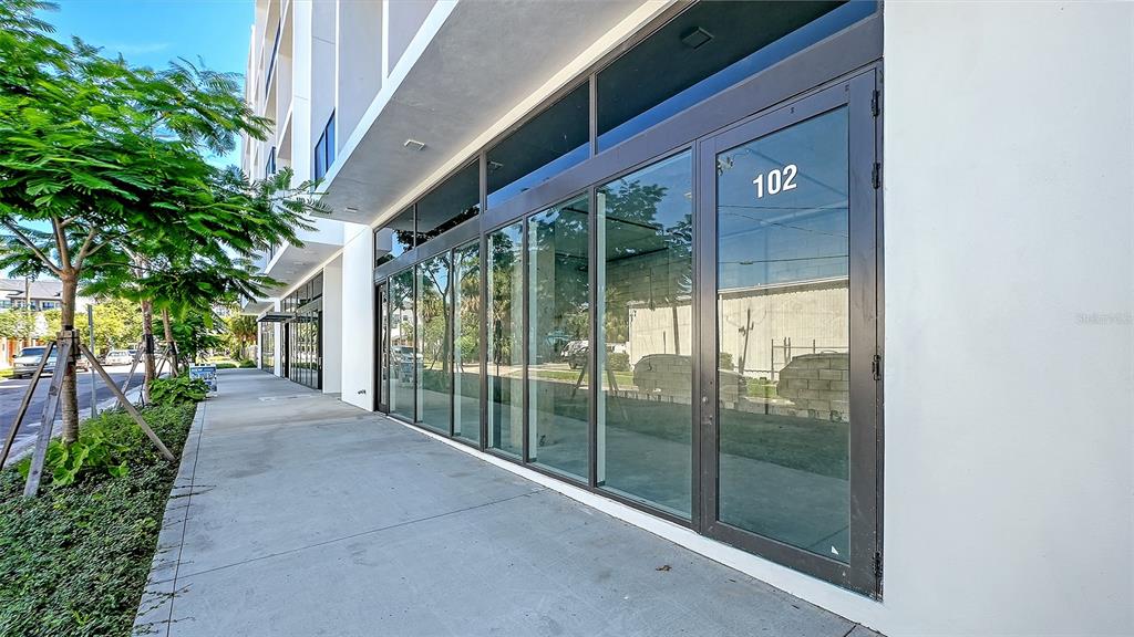 A modern commercial storefront with large glass windows and a door marked 102 — 430 KUMQUAT COURT UNIT 102, SARASOTA, FL