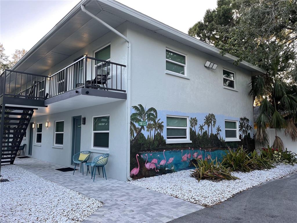 A two-story building exterior features a flamingo mural, a balcony, and a paved walkway — 1910 MORRILL STREET UNIT 1, SARASOTA, FL