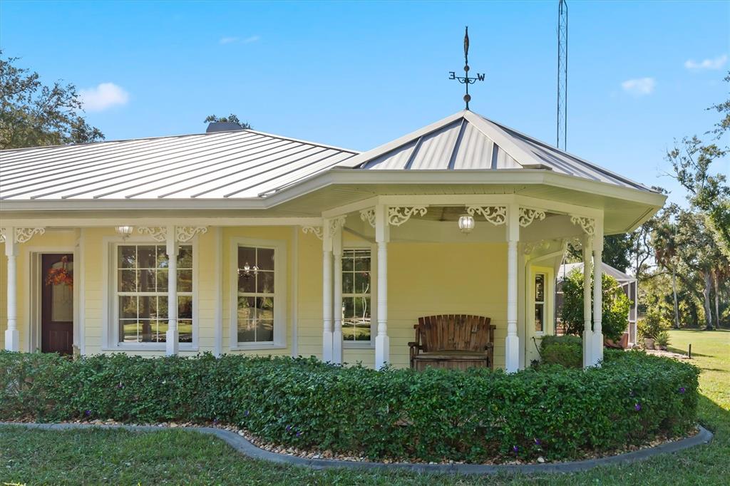 A yellow house with a metal roof, a wrap-around porch, and a decorative weather vane — 3971 NE ALBIN AVENUE, NORTH PORT, FL