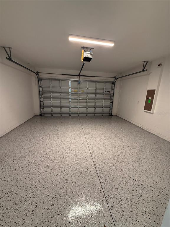 A clean, empty garage features a speckled epoxy floor and a metal overhead door — 5853 WINDBREAK COURT, APOLLO BEACH, FL