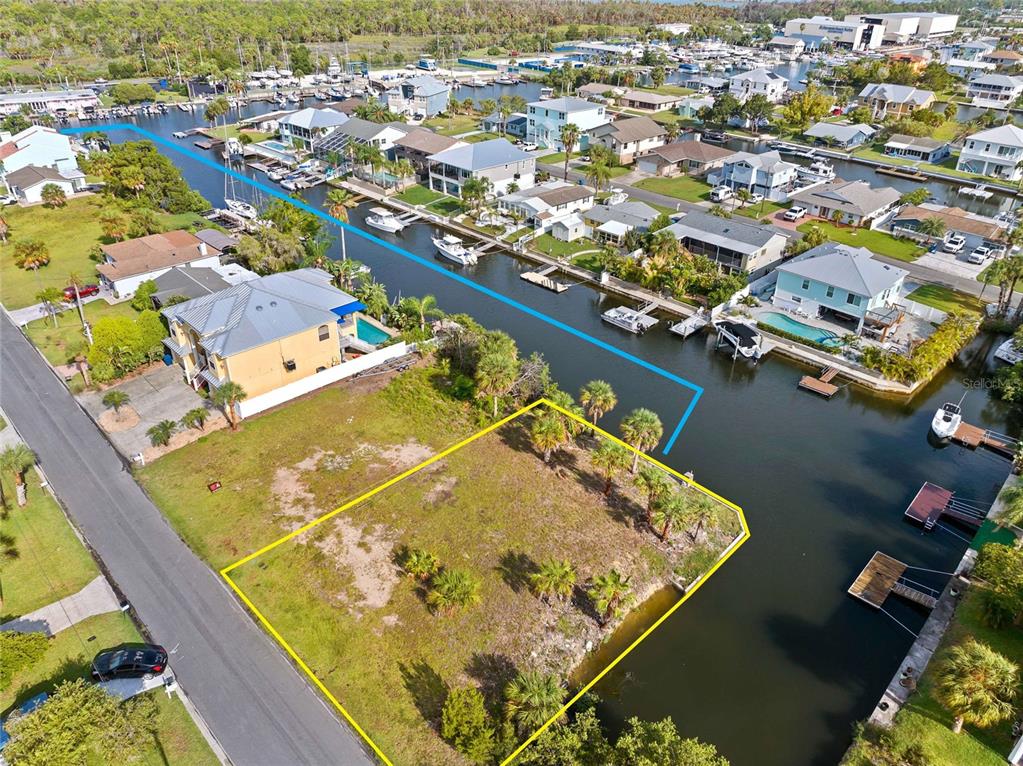 An aerial view shows a vacant waterfront lot outlined in yellow next to a house — 4342 TAHITI DRIVE, HERNANDO BEACH, FL
