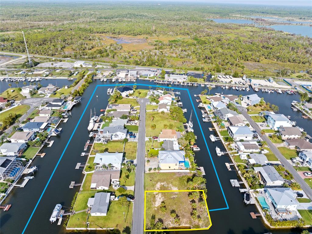 An aerial view shows a vacant waterfront lot outlined in yellow next to a residential house — 4342 TAHITI DRIVE, HERNANDO BEACH, FL