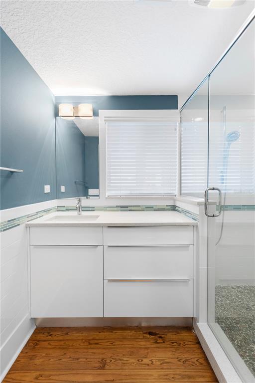 A bathroom features a white vanity, a glass-enclosed shower, and blue walls over white tile — 1950 ADAMS LANE, SARASOTA, FL