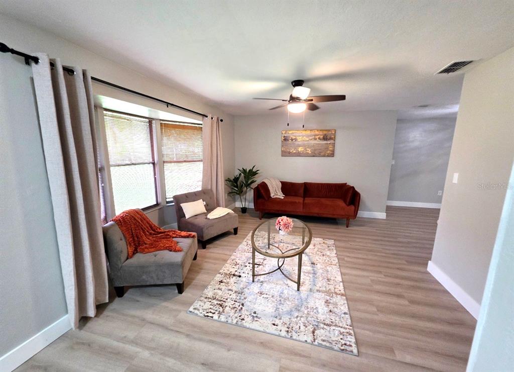 A living room features light wood flooring, a gray sectional sofa, and a bay window — 162 W MASSACHUSETTS STREET, HERNANDO, FL