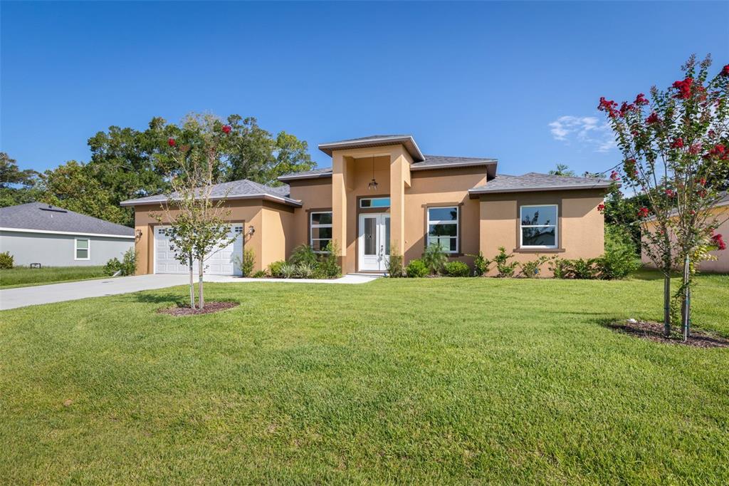 A single-story tan stucco house with a prominent entryway and a two-car garage — 57 FLAMINGO DRIVE, PALM COAST, FL