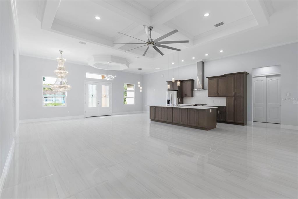 A spacious, open-concept kitchen and living area features white tile floors, dark cabinetry, and a tray ceiling — 57 FLAMINGO DRIVE, PALM COAST, FL