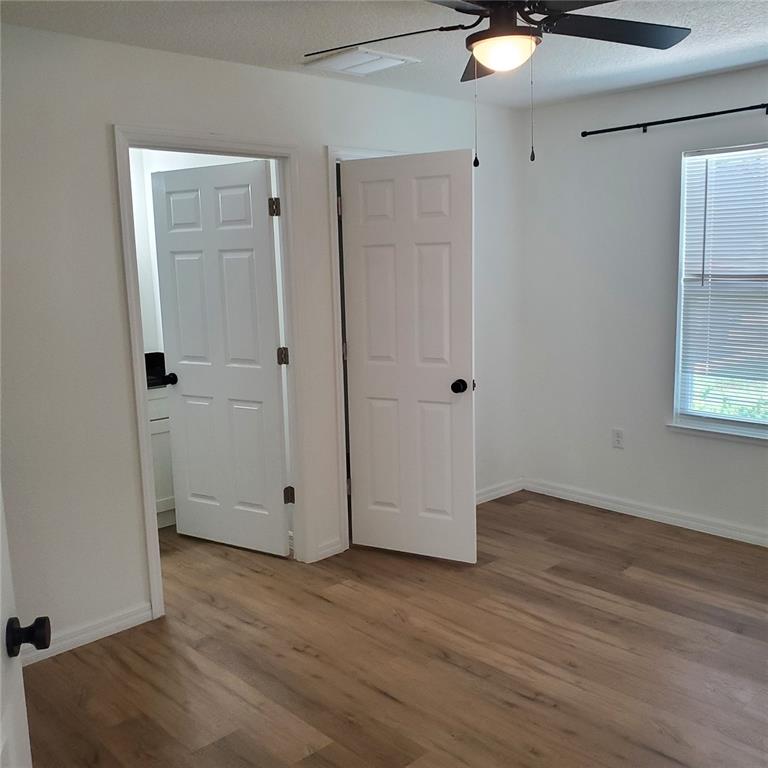 A bedroom with white walls, wood-look flooring, a ceiling fan, and two interior doors — 353 FISHER WAY, OCKLAWAHA, FL