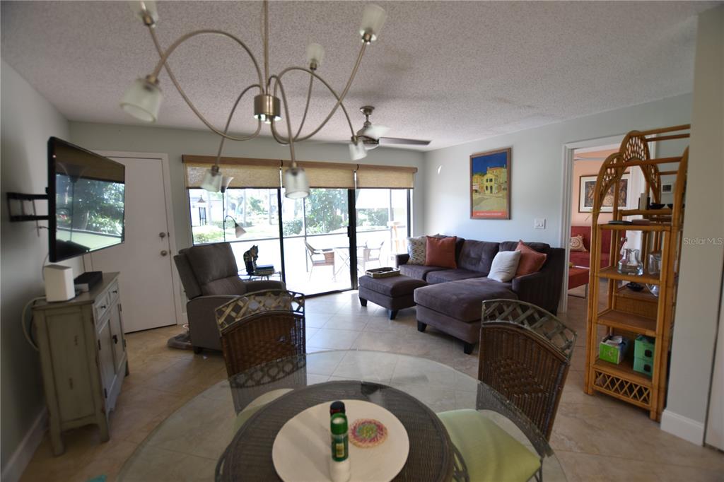 A living and dining area features tile floors, a sectional sofa, and a glass-topped table — 4610 RINGWOOD MEADOW UNIT 17, SARASOTA, FL