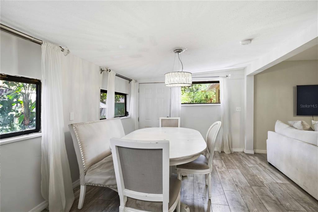 A dining room features a white oval table, upholstered chairs, a bench, and wood flooring — 603 60TH AVENUE W, BRADENTON, FL