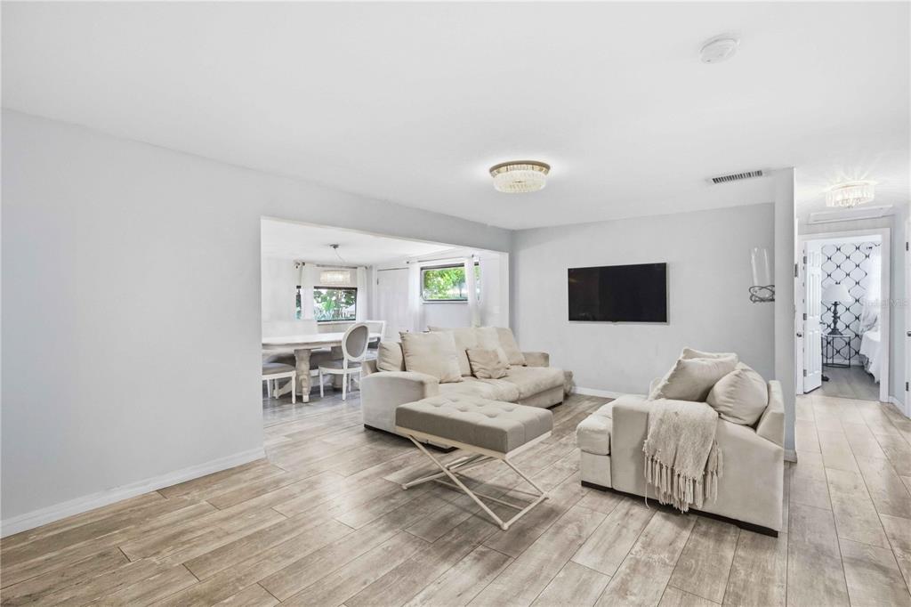 A living room with light wood-look flooring, neutral furniture, and an adjacent dining area — 603 60TH AVENUE W, BRADENTON, FL