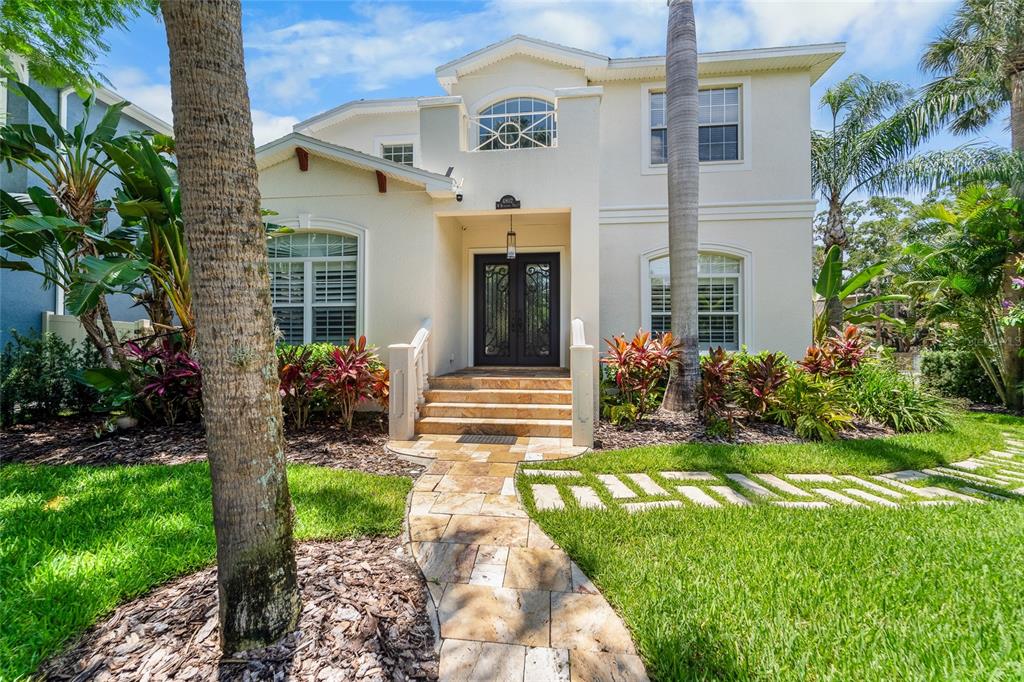 A two-story stucco house features a stone walkway, arched windows, and a dark double-door entrance — 4802 W BEACHWAY DRIVE, TAMPA, FL