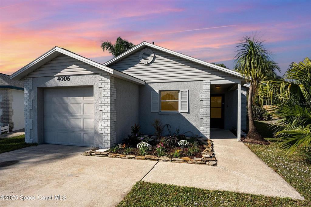A single-story house with a gray stucco exterior, a one-car garage, and a front walkway — 4006 DEWBERRY CIRCLE, MELBOURNE, FL