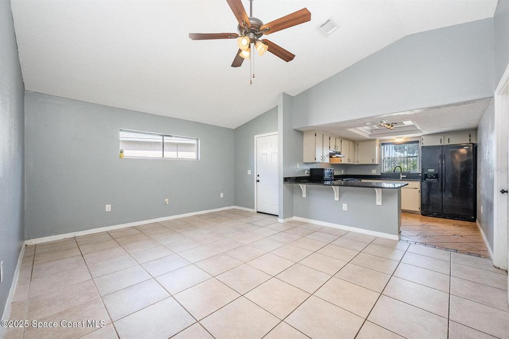 An open-concept living area features light gray walls, tile flooring, and an adjacent kitchen — 4006 DEWBERRY CIRCLE, MELBOURNE, FL