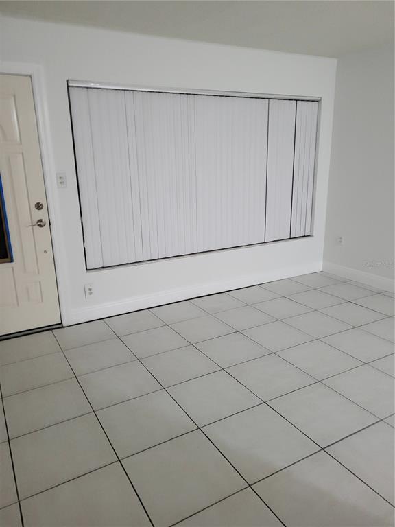 An empty room with white walls, large vertical blinds, and light-colored tiled flooring — 10803 N ARMENIA AVENUE, TAMPA, FL