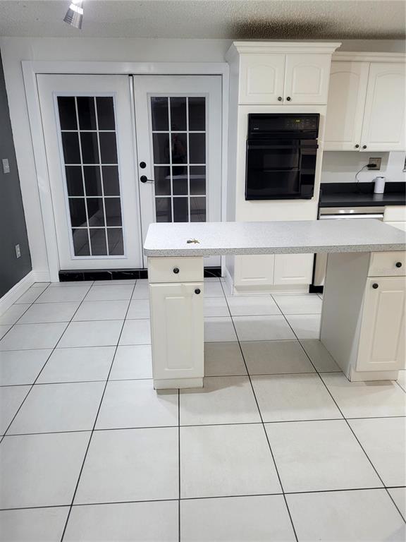 A kitchen features white cabinets, a wall oven, a central island, and tiled flooring — 10803 N ARMENIA AVENUE, TAMPA, FL