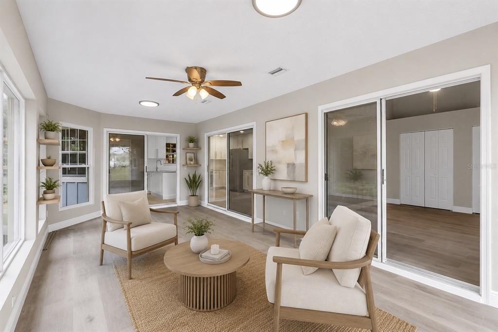 A sunroom with light wood flooring, two armchairs, a coffee table, and sliding glass doors — 22 WEIDNER PLACE, PALM COAST, FL