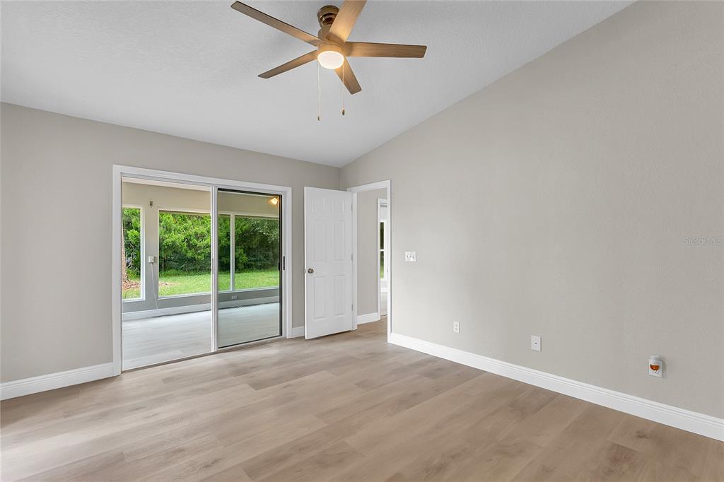 A bedroom with light wood-look flooring, a ceiling fan, and sliding glass doors to a patio — 22 WEIDNER PLACE, PALM COAST, FL