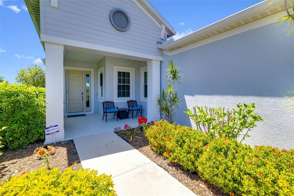 A walkway leads to the covered front porch of a house with light blue siding — 13638 OLD CREEK CT, PARRISH, FL