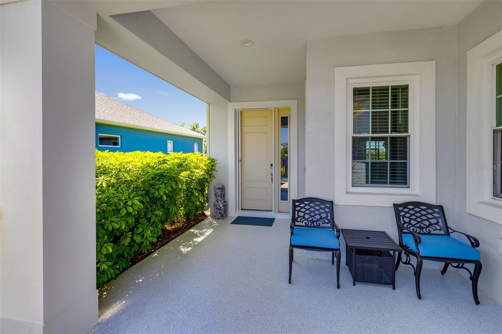 A covered front porch features two chairs, a small table, and a light-colored door — 13638 OLD CREEK CT, PARRISH, FL