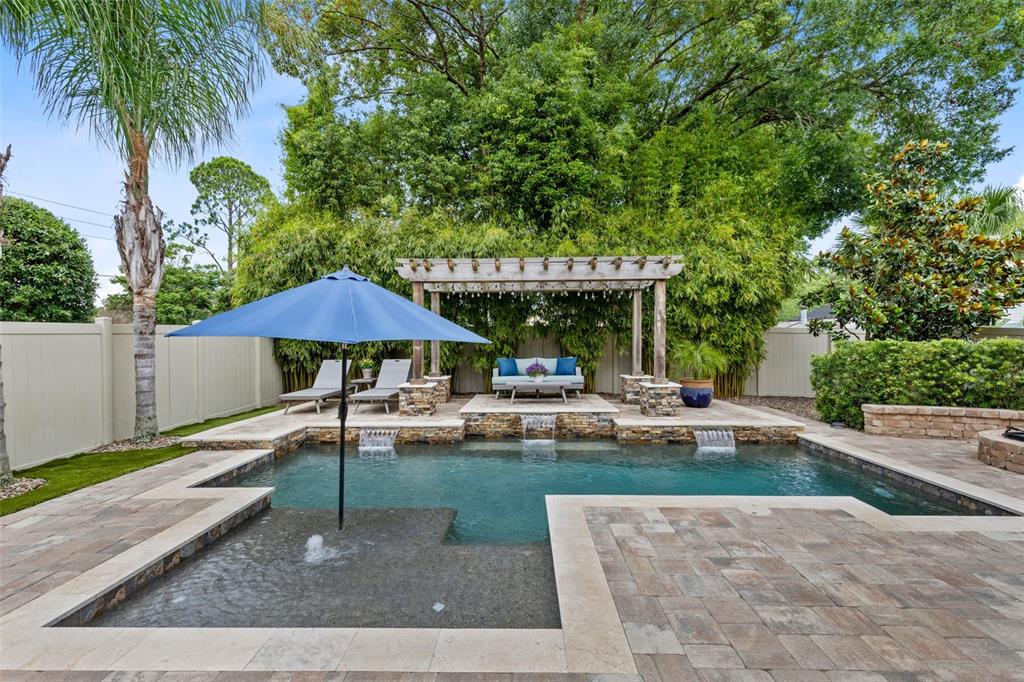 A backyard swimming pool features a tanning ledge, water fountains, and a wooden pergola — 1448 LAKE FLORENCE WAY, WINTER PARK, FL