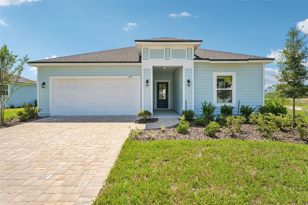 A light blue single-story house features a white garage door and a paved driveway — 373 SILVER LILY WAY, ST AUGUSTINE, FL