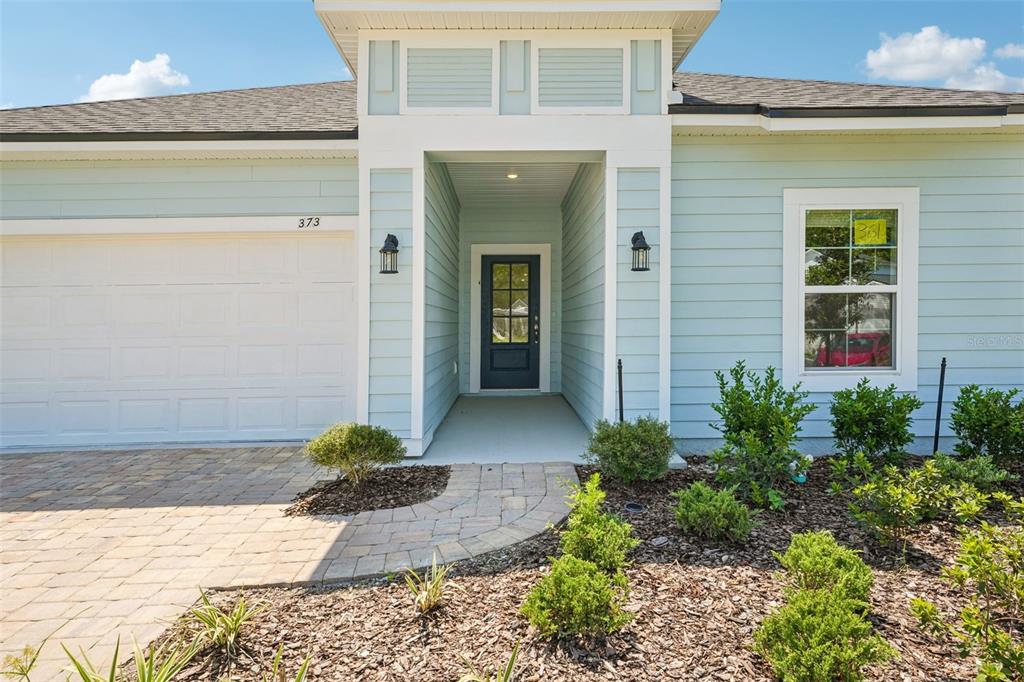 The exterior of a light blue house features a white-trimmed entryway and a paved walkway — 373 SILVER LILY WAY, ST AUGUSTINE, FL