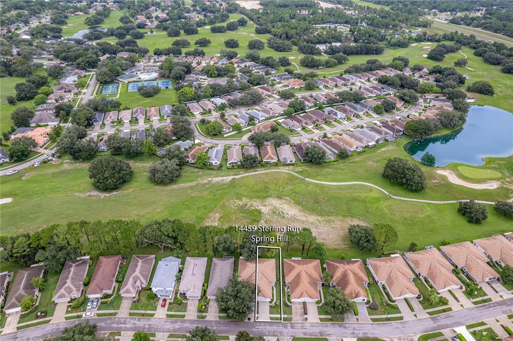 An aerial view shows a residential neighborhood with a highlighted house bordering a golf course — 14459 STERLING RUN, SPRING HILL, FL