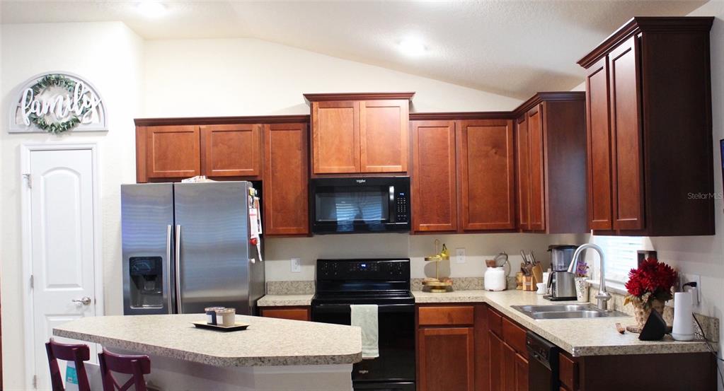 A kitchen features dark wood cabinets, stainless steel appliances, and a light-colored countertop island — 826 LANDMARK HILLS DRIVE, HAINES CITY, FL