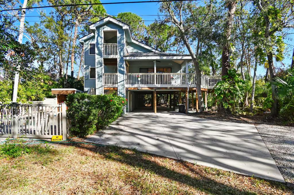 A light blue two-story stilt house with a large deck and concrete driveway — 13837 76TH AVENUE, SEMINOLE, FL