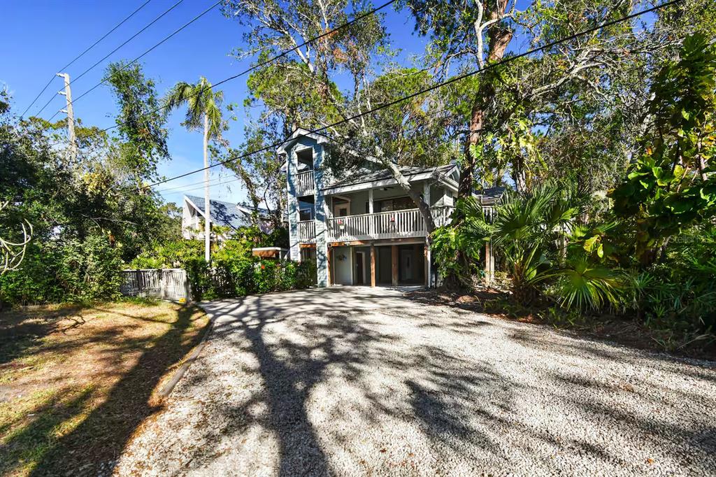 A two-story house with a gravel driveway, wooden balcony, and surrounding trees — 13837 76TH AVENUE, SEMINOLE, FL