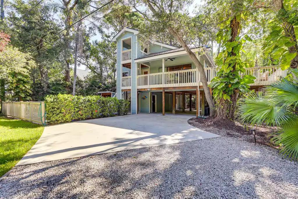 A light green elevated house with a large wooden deck and a concrete driveway — 13837 76TH AVENUE, SEMINOLE, FL