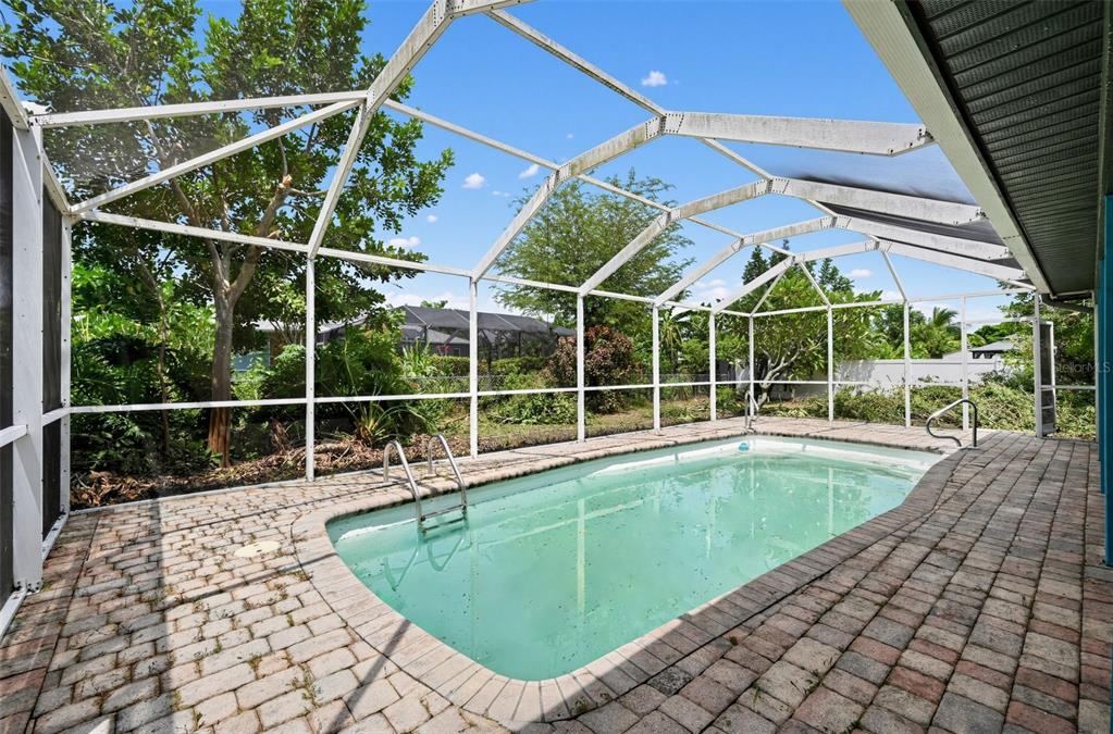 A rectangular swimming pool sits on a brick patio inside a screened-in lanai enclosure — 1325 SW 25TH TERRACE, CAPE CORAL, FL