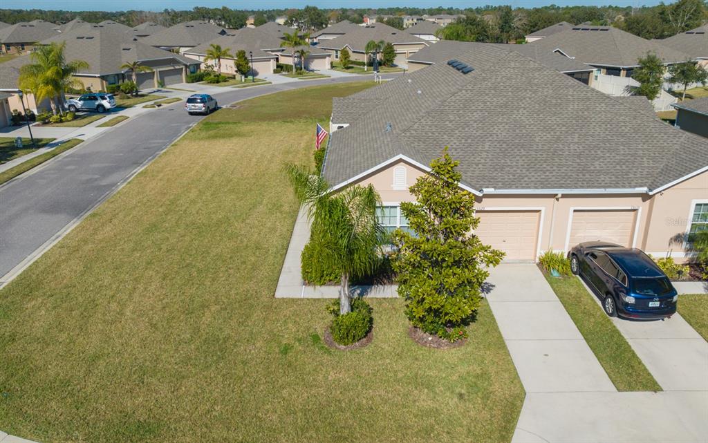 An aerial view shows a suburban house with a tan exterior, two-car garage, and lawn — 13529 CREST LAKE DR, HUDSON, FL