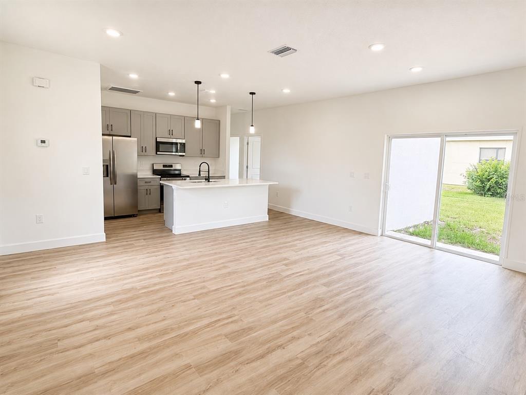 A kitchen with gray cabinets and an island opens into a living area with sliding doors — 441 CARAWAY DRIVE, KISSIMMEE, FL