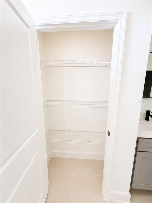 A small closet with three white wire shelves and light-colored tile flooring — 441 CARAWAY DRIVE, KISSIMMEE, FL