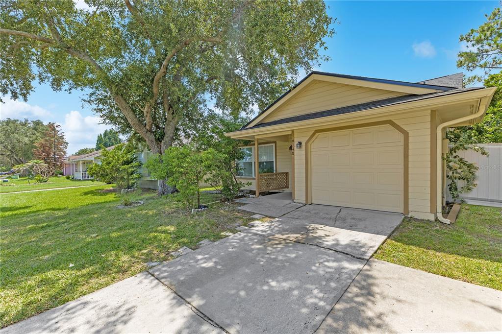 A tan single-story house features a one-car garage, a concrete driveway, and a large tree — 9148 DUBOIS BOULEVARD, ORLANDO, FL