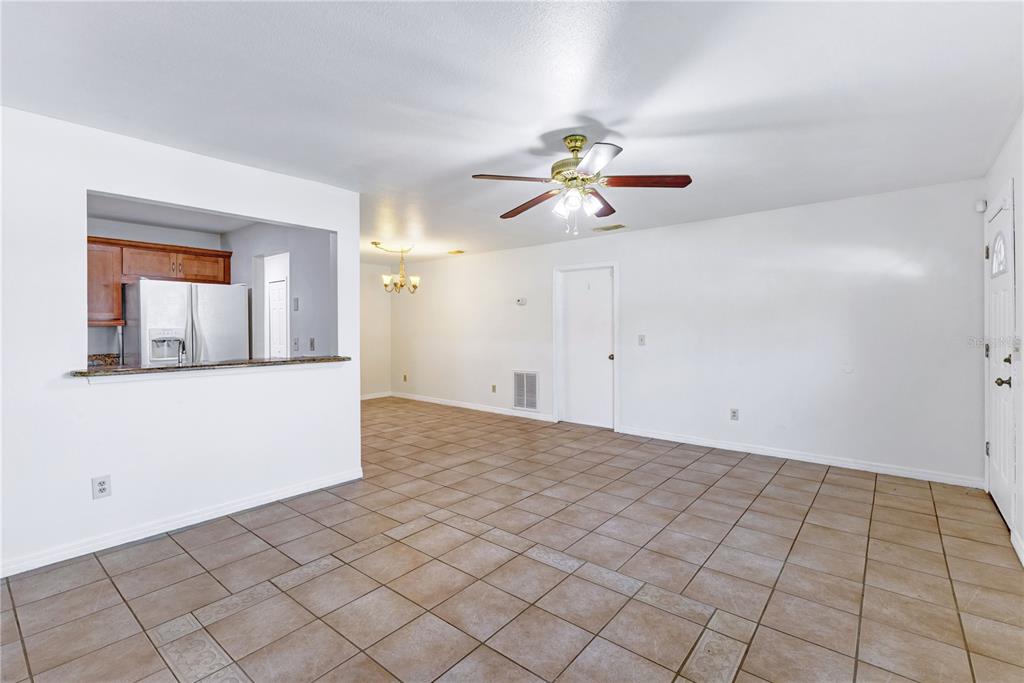 An open-concept living and dining area features tile flooring, a ceiling fan, and kitchen pass-through — 9148 DUBOIS BOULEVARD, ORLANDO, FL
