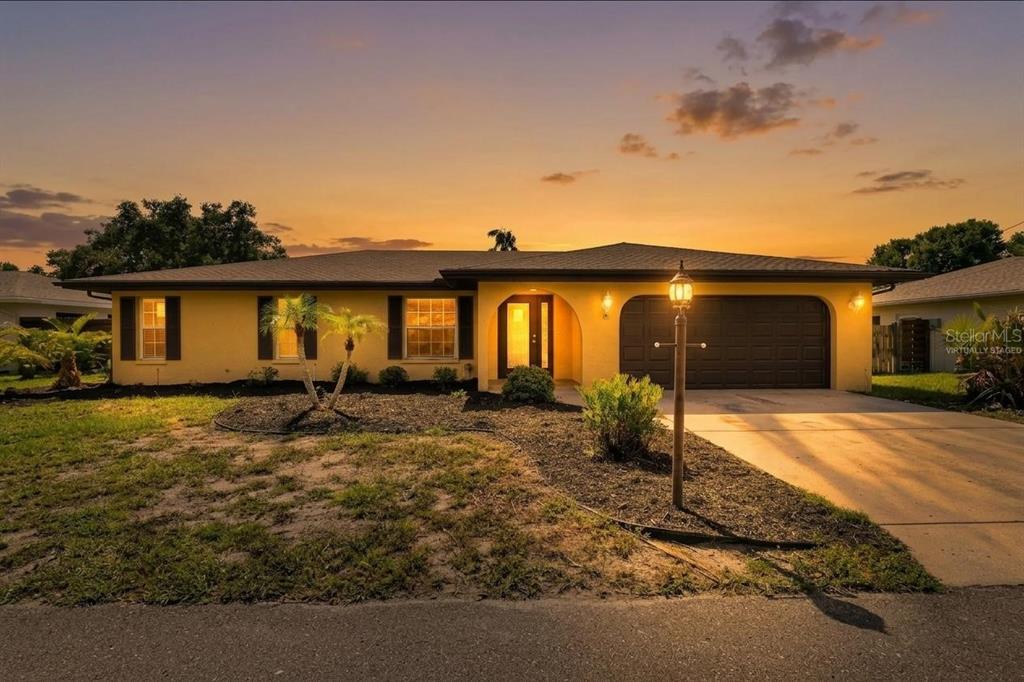 A yellow single-story house with a dark garage and a lamp post at sunset — 1304 71ST STREET NW, BRADENTON, FL