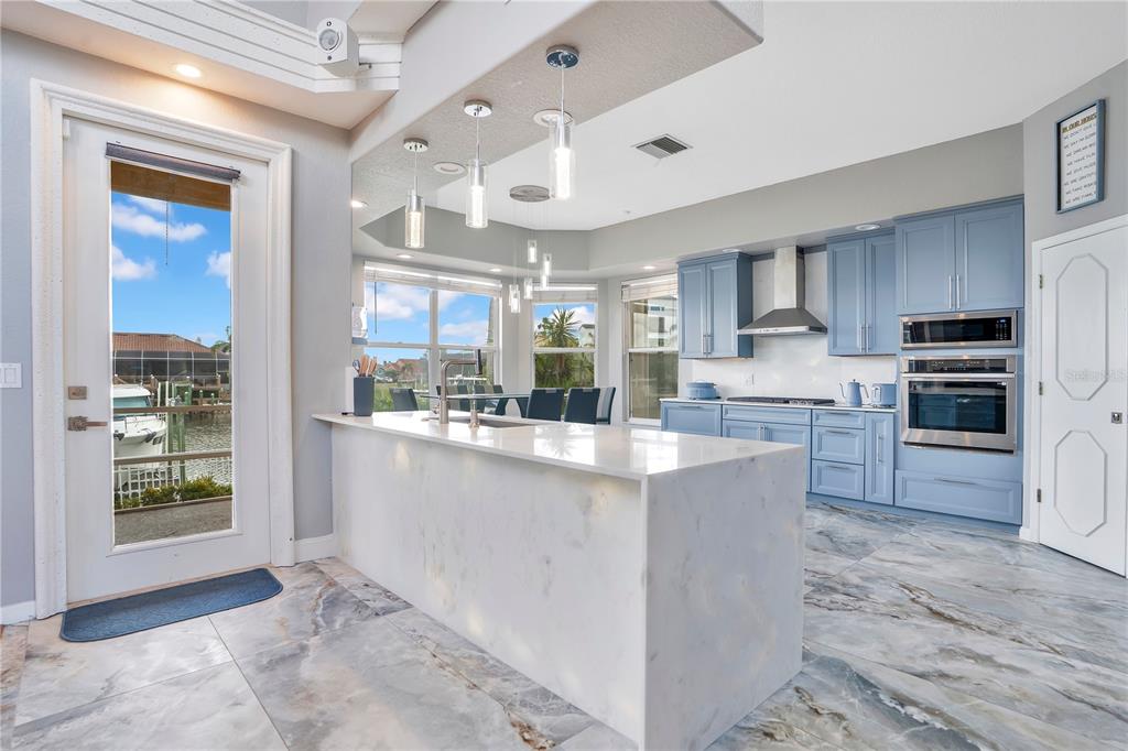 A kitchen with light blue cabinets, a white waterfall island, and views of a canal — 934 SYMPHONY ISLES BOULEVARD, APOLLO BEACH, FL