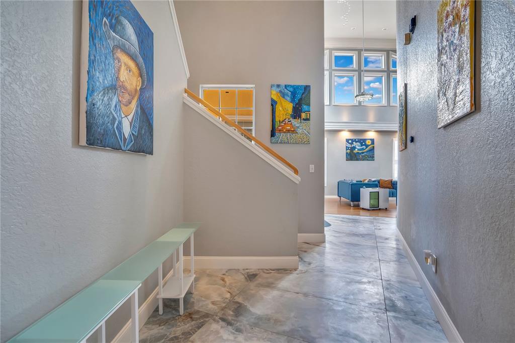 A tiled entryway features a staircase, a long console table, and several Van Gogh paintings — 934 SYMPHONY ISLES BOULEVARD, APOLLO BEACH, FL