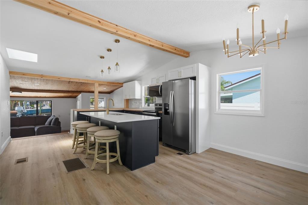 A kitchen with a dark island, stainless steel refrigerator, and wood-look flooring — 7037 MCCRAY DRIVE, HUDSON, FL