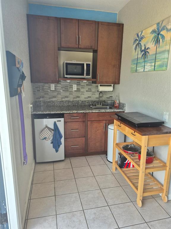 A kitchen area features a wooden cart, a white desk with a stool, and tiled flooring — 389 NOLANE LANE, POLK CITY, FL