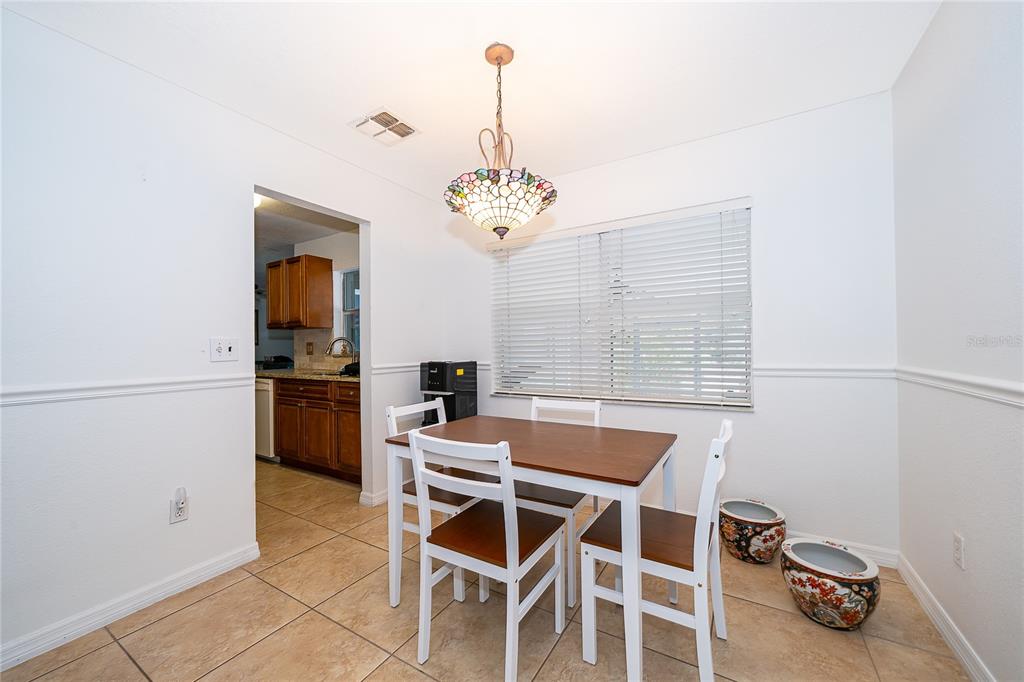 A living room with tile floors, a treadmill, a brown leather sofa, and a dining area — 103 KILKENNY COURT, LONGWOOD, FL