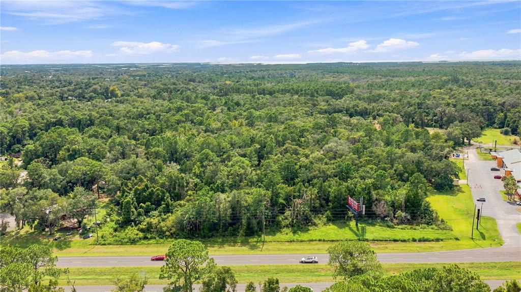 An aerial view shows a large, wooded plot of land bordering a multi-lane highway — 4366 N SUNCOAST BOULEVARD, CRYSTAL RIVER, FL